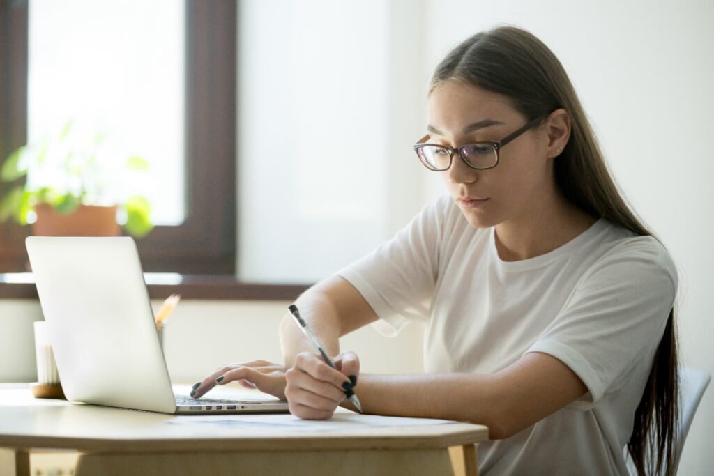 Mulher de óculos fazendo curso de IA gratuito em notebook
